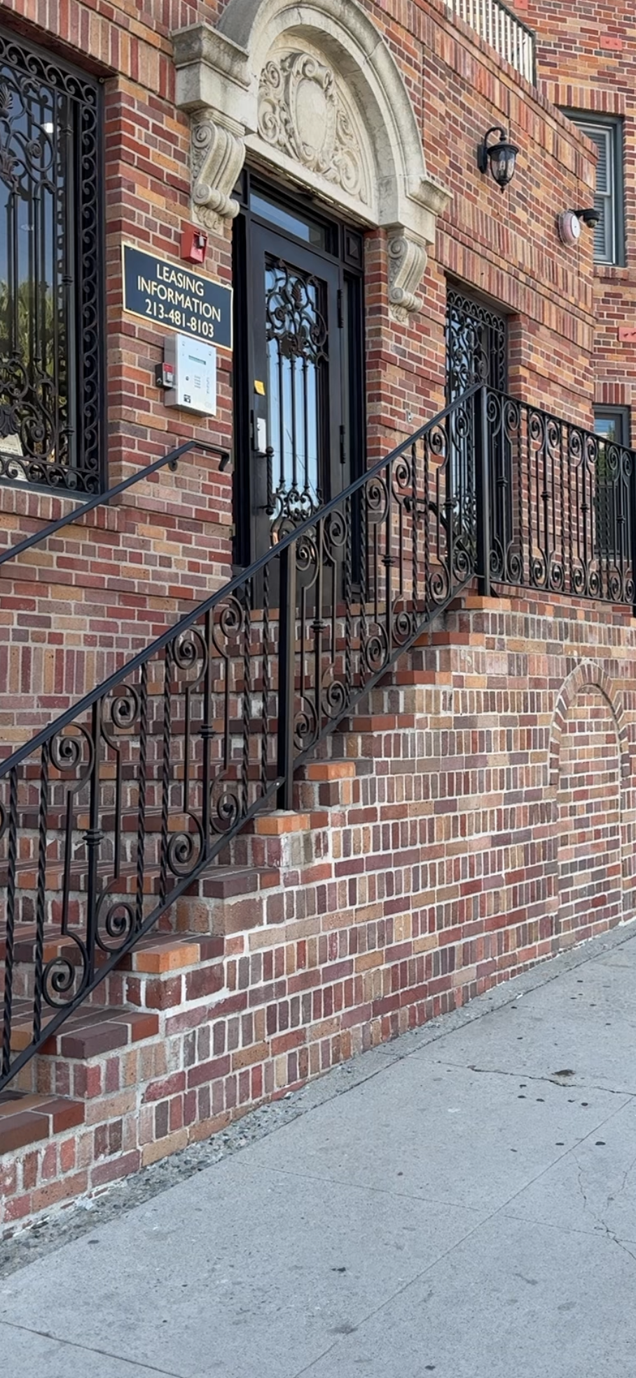 The front of a brick apartment with a large staircase