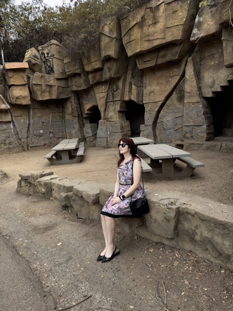 A woman sits at the old LA Zoo with its abandoned enclosures